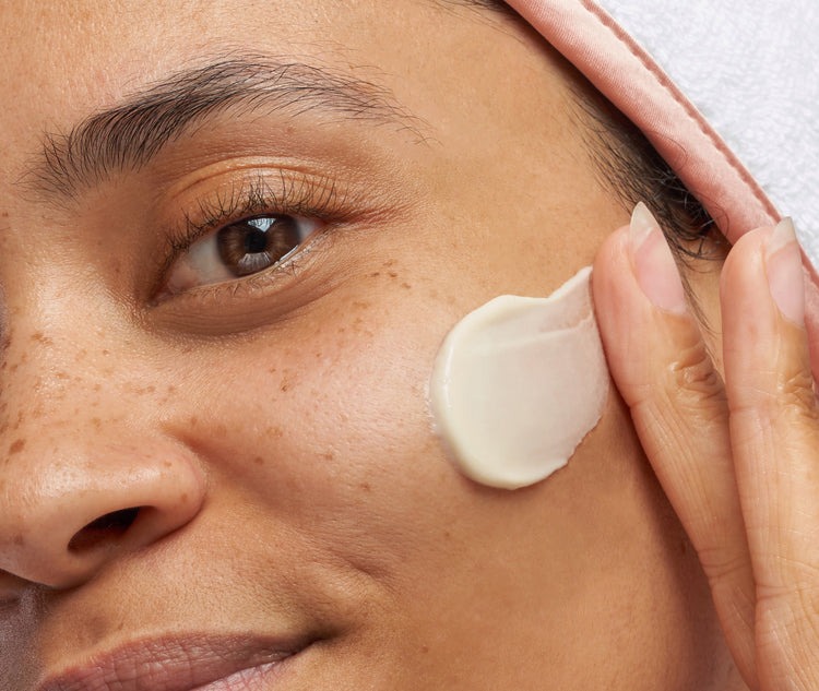 Woman applying skincare product to her cheek
